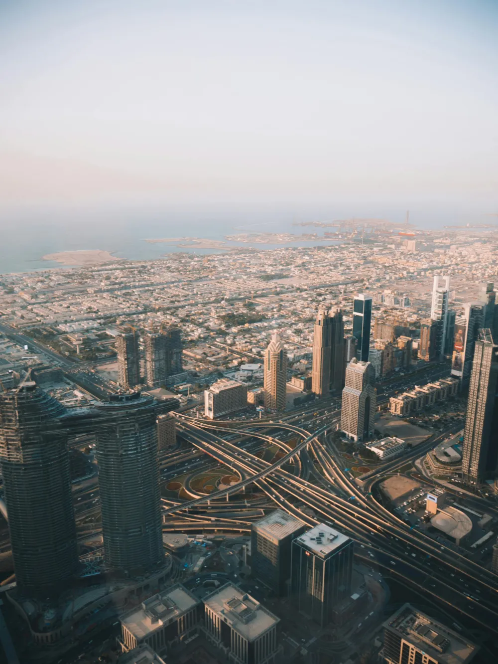 A stunning aerial view of Dubai's modern skyscrapers and complex highways during the day.