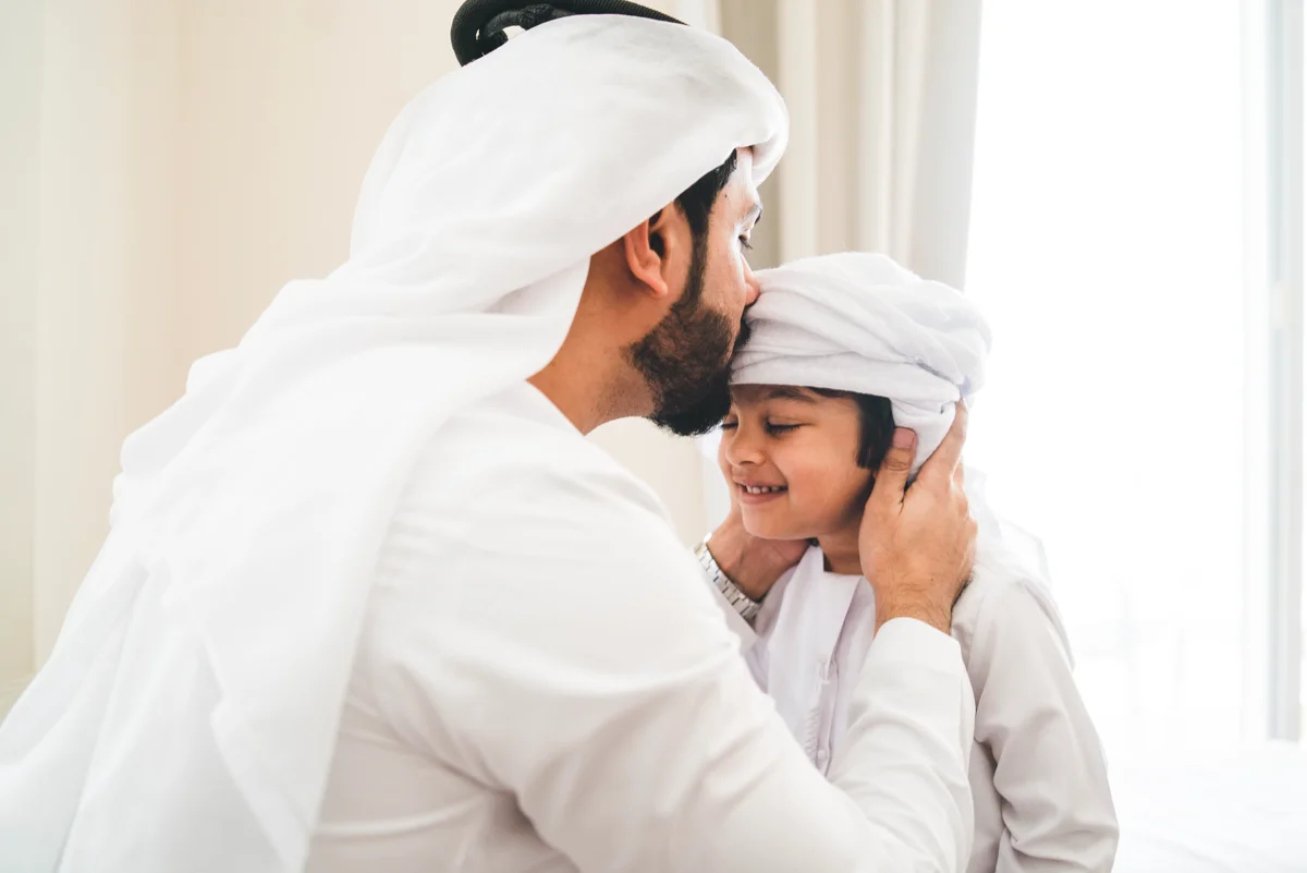Arab man fixing keffiyeh to his son